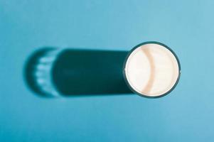 vaso de leche vista superior con una sombra dura sobre fondo azul. foto
