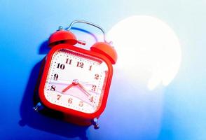 Red retro style analog alarm clock uner the bright light. photo