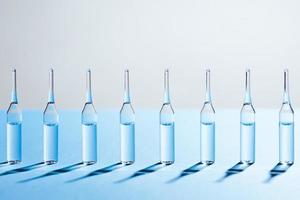 Group of glass ampules standing in a row on blue background. photo