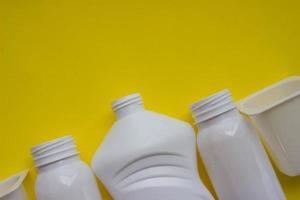 White plastic bottles on yellow background with place for your design. Top view photo