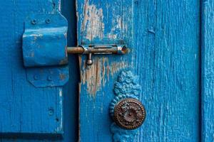 The old latch lock the blue wooden doors. An old round handle on the door. Parched boards. Village life photo