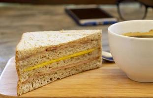 sandwich on a wooden tray with a cup of coffee on a concrete table photo