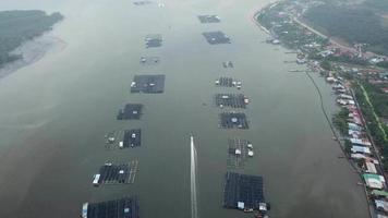 Fishing boat sail between the fish farm on to sea at river mouth video