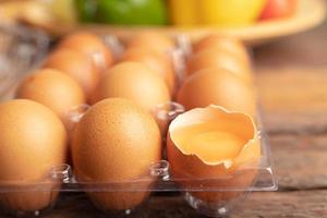 eggs of chicken and yolk with broken in plastic box on the wooden table photo