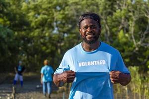 retrato de un voluntario afroamericano que disfruta del trabajo social caritativo al aire libre en un proyecto de plantación de manglares foto