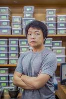 Asian man is standing in front of the herbs self in Thai Heab store. Bangkok. Thailand. photo