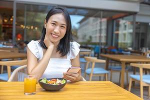 Woman eating Breakfast and play smart phone. Fruits such as watermelon, papaya, melon, passion fruit, orange juice and coffee. placed on a gray placemat photo