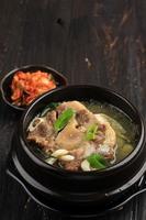 Gori Gomtang  or Korean Beef Oxtail Stew Soup, Served in the Black Korean Bowl with Kimchi and Sliced Green Onion photo