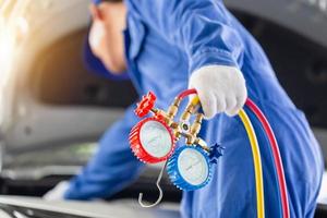 Repairman holding monitor tool to check and fixed car air conditioner system, Technician check car air conditioning system refrigerant recharge, Air Conditioning Repair photo