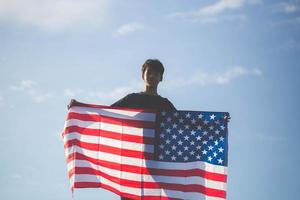 Silhouette of boy holding USA flag, man is holding waving american USA flag photo