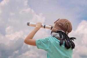 Asian child girl with clipping path looking in spyglass, Happy kid playing outdoors photo