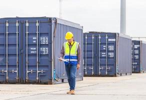 Engineer with clipboard checklist in industry containers cargo, Foreman dock worker in hardhat and safety vest control loading containers box from cargo photo
