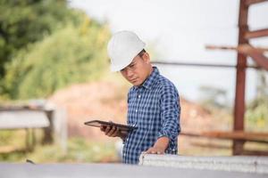 Engineer man checking project at building site, Foreman in hardhat with digital tablet at infrastructure construction site photo