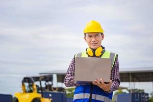 Engineer man with laptop checking and inspect the container, Foreman in hardhat and safety vest checking containers box from cargo photo