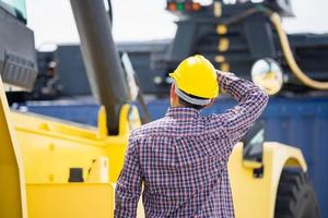 Back view of Foremen in hard hat control loading containers box from cargo, Engineer checking and inspect container in industry cargo photo