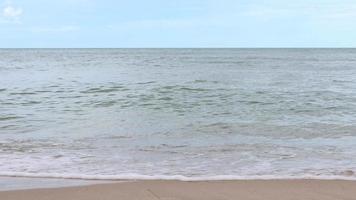 wind waait over zee golven op het strand overdag. de golven die het lege zandstrand raken. video