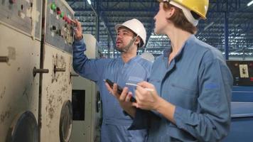 Professional industry engineer teams in hard hats and safety uniforms inspect machine's control panel, maintenance check with tablet in mechanical manufacture factory, electrical service occupation. video