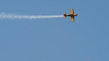 avión deportivo amarillo vuela alto en el cielo realizando acrobacias espectaculares