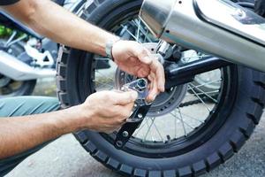 cierre la mano del trabajador técnico, la rueda fija de la motocicleta en el exterior del garaje. foto