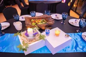 las velas románticas están decoradas en la mesa de la cena con una caja cuadrada de madera blanca y un pequeño árbol encima. foto
