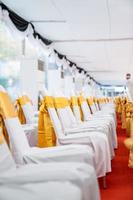 Temporary Air Conditioner indoor tent for outdoor event in the day. Inside Tents has red carpet and a lot of chair covered by white cloth and golde ribbon on it. photo