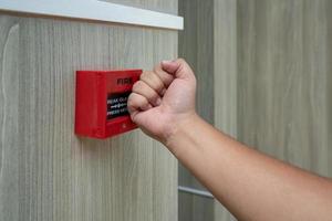 Fire alarm box with human hand action to crush the glass for emergency situation. photo