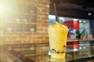 Mango fruity frappe, smoothies and shakes in plastic take away cup on the wooden table in beverage shop. photo