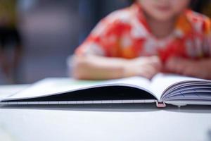 Asian girl kid concentrated read a book, close up at the book. photo