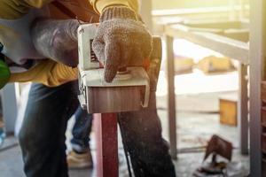 Carpenter is shaving red wood door by his shaving machine in outdoor field with steel pole building structure environment. photo