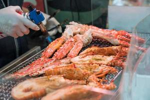 Grilled shrimps and crab on the grill are fire and cooked in fish market, Japan photo