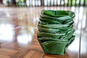 Envases ecológicos de comida en bandeja locales y tradicionales hechos para platos y cuencos a partir de hojas de plátano, dispuestos juntos como una torre. foto