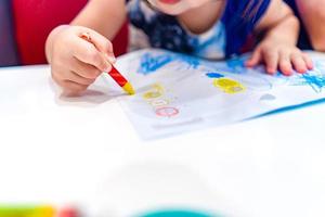 Kid play, study and learn how to color and draw the crayon color in to the paper with her parents. photo