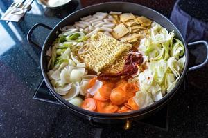 Tokboki Korean traditional food hot and spicy rice cake, combination and apply puff with cheese and vegetable on the black table photo