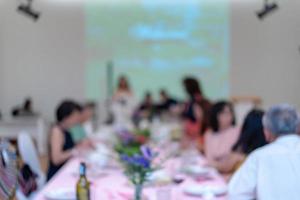 comedor borroso con el proyector y la pantalla blanca para el público asiático sentado en la larga fila de mesas. foto