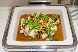 steaming fish in large white square bowl at Thailand resort. photo