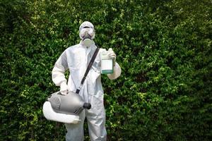 Professional technical man in prevention suit with his sterilizing machine and disinfecting water in his hand. He is ready to take purifying coronavirus COVID-19 out. Clipping Path. photo