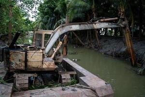 old loading and digging excavator on the holding water surface for digging soil in the canal photo
