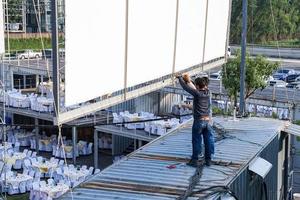 two worker setup outdoor canvas billboard on the rooftop of container. photo