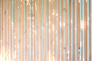 Wood battens in the vertical postion settle on the wall for fence and hording outside of building. It's a background of light from leaf of tree shadow to battens. photo