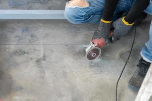 Construction worker is cutting the floor by medium blade machine to circle hold shape with a lot of dust around it for install closet with. photo