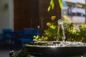 primer plano de una pequeña fuente de palo de bambú dentro de un frasco verde vintage que decoraba el jardín con efecto de luz solar. foto