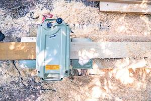 worker scrubs the big long wood plate with polishing machine in the garden. photo