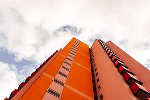 a high-rise with small red balkons with a view from below photo