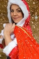 Beautiful girl Santa carrying bag of presents photo