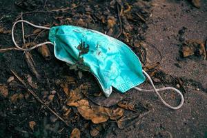 Discarded dirty surgical mask lying on the ground photo