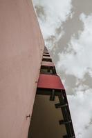 a high-rise with small red balkons with a view from below photo