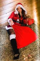 Beautiful girl in Santa costume sits on straw