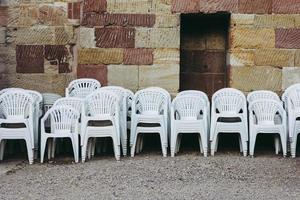 plastic chairs stacked in front of brick wall photo