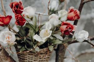 an old flower basket with roses in front of a brick wall photo