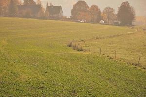 Misty farm field with distant house